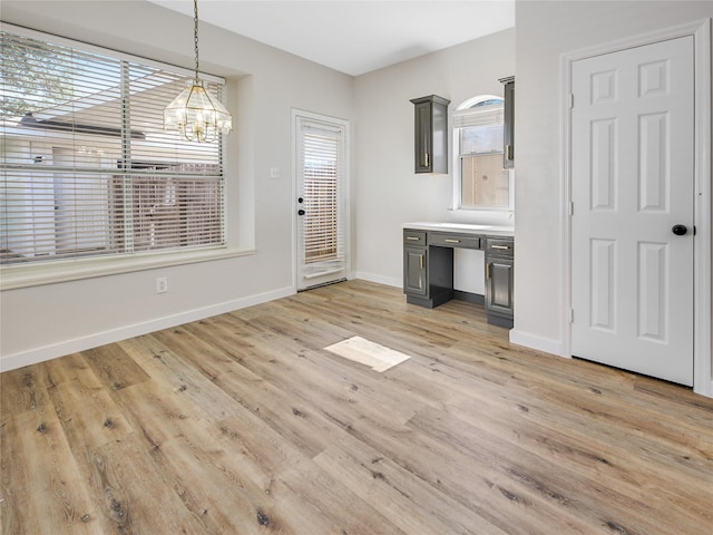 unfurnished dining area featuring light wood finished floors, baseboards, and an inviting chandelier
