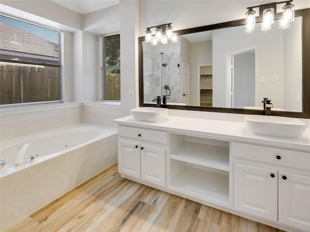 bathroom with a sink, a bath, a marble finish shower, and wood finished floors