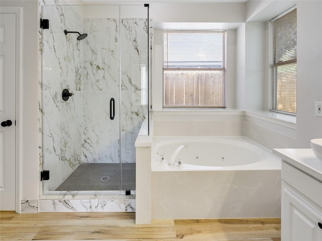 full bathroom with wood finished floors, a marble finish shower, a tub with jets, and vanity