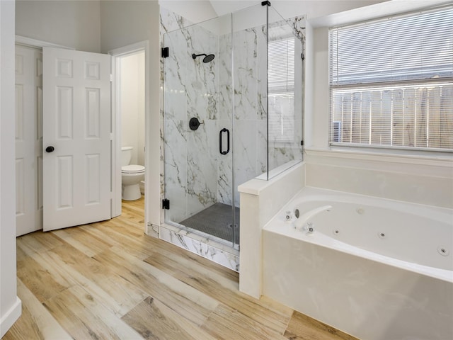 bathroom with a whirlpool tub, toilet, a marble finish shower, and wood finished floors