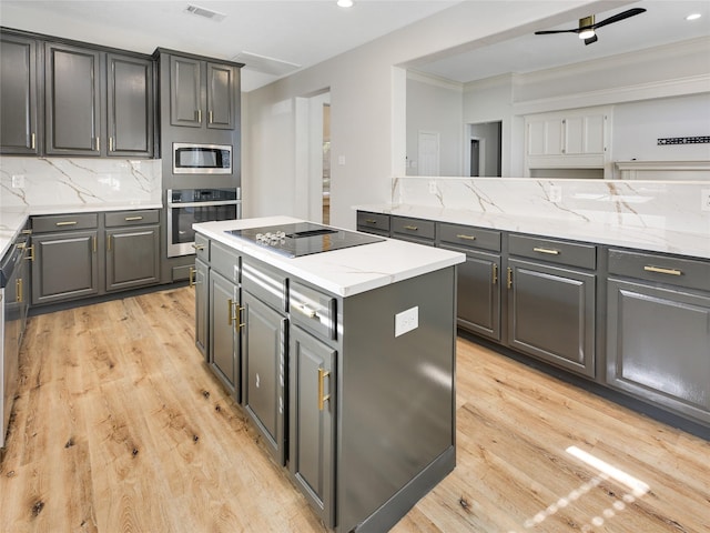 kitchen with stainless steel appliances, a kitchen island, light wood finished floors, and gray cabinets