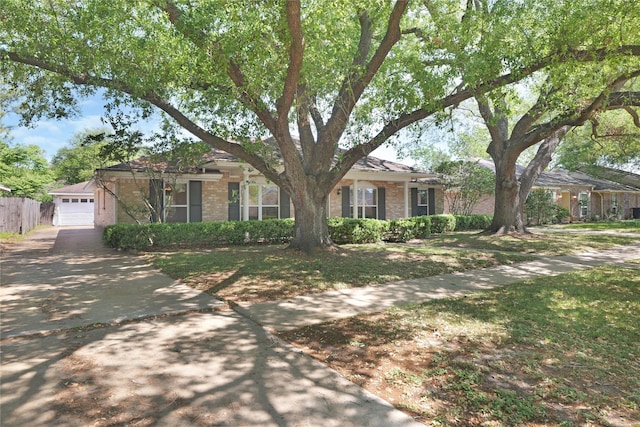single story home featuring brick siding, a detached garage, and fence