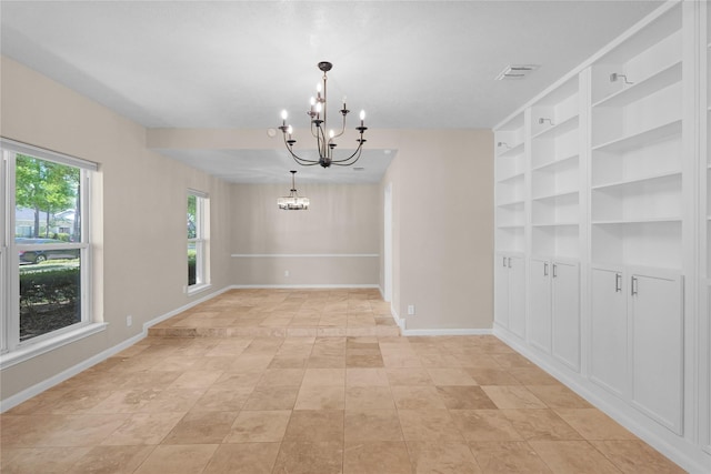 unfurnished dining area featuring visible vents, built in shelves, baseboards, light tile patterned floors, and a notable chandelier