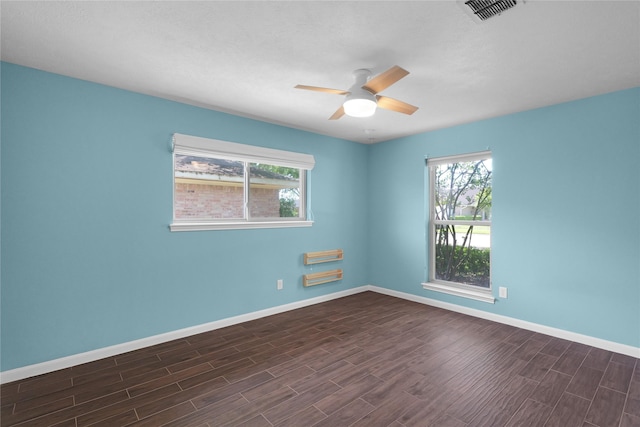 empty room with visible vents, ceiling fan, baseboards, and dark wood-style floors
