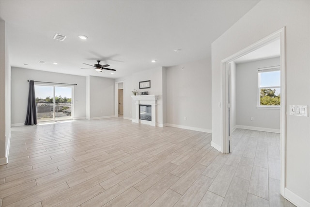 6804 Westview Dr Unit 1407, Houston, TX 77055 - unfurnished living room with baseboards, a glass covered fireplace, ceiling fan, visible vents, and light wood-type flooring