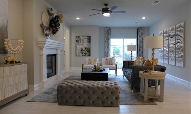living area featuring a glass covered fireplace, visible vents, baseboards, and ceiling fan