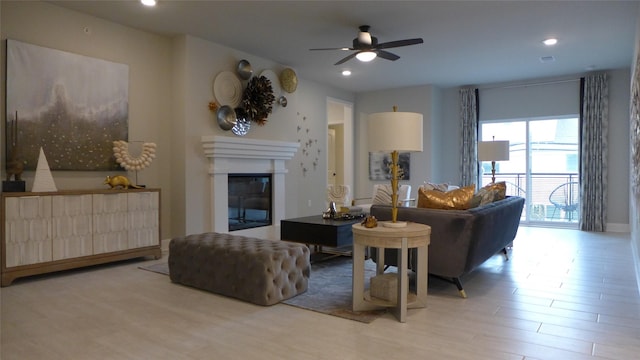 living room featuring a glass covered fireplace, recessed lighting, a ceiling fan, and wood finished floors