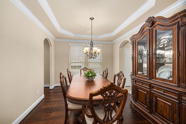dining space featuring dark wood-style flooring, crown molding, arched walkways, an inviting chandelier, and a tray ceiling