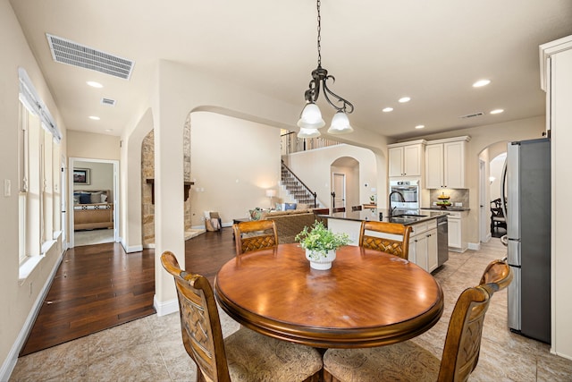 dining room featuring visible vents, arched walkways, stairs, and baseboards