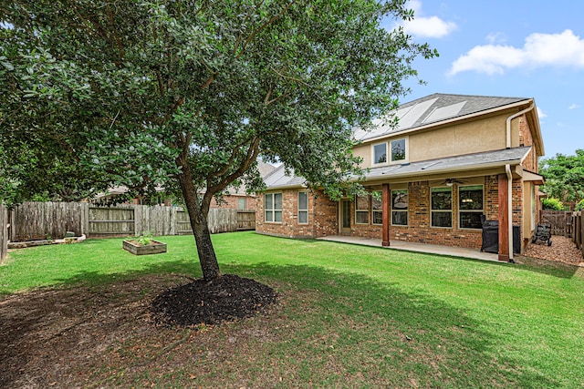 rear view of property featuring a fenced backyard, ceiling fan, a lawn, and a patio area