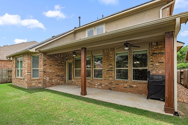 back of property with a yard, ceiling fan, and fence