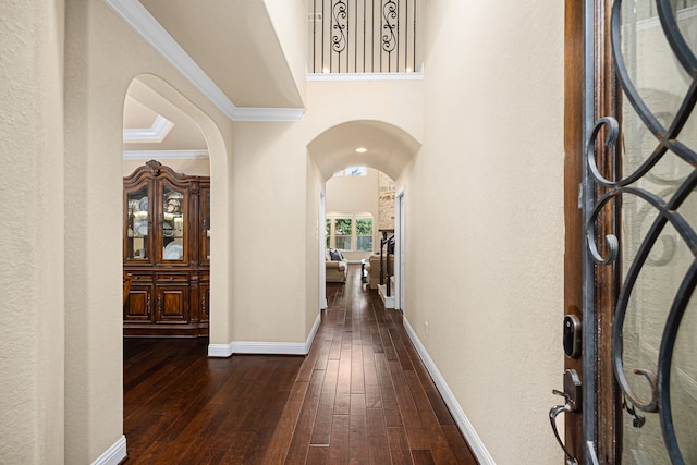 hallway featuring arched walkways, ornamental molding, baseboards, and dark wood-type flooring