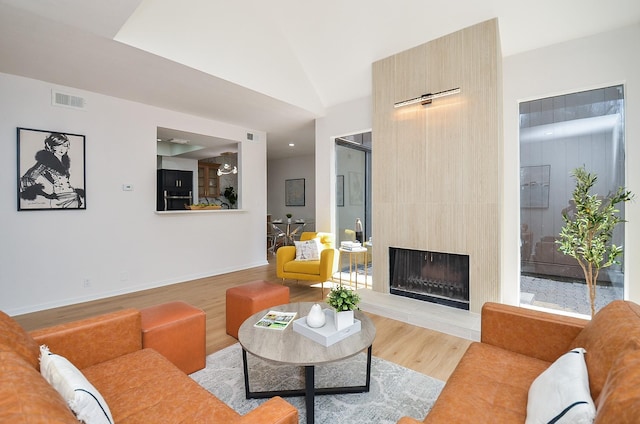 living room featuring visible vents, baseboards, wood finished floors, and a fireplace