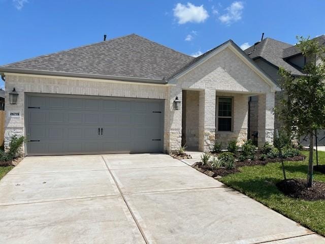 26719 Grandiflora Dr, Magnolia, TX 77355 - view of front facade with concrete driveway, an attached garage, roof with shingles, and stone siding