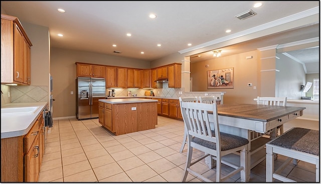 kitchen featuring light tile patterned floors, a center island, stainless steel refrigerator with ice dispenser, and decorative backsplash