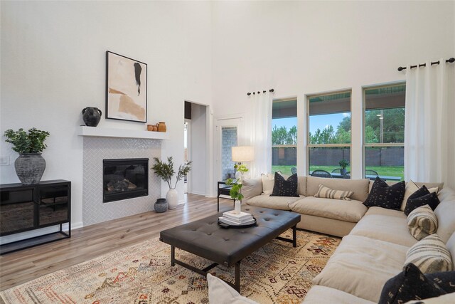 26723 Grandiflora Dr, Magnolia, TX 77355 - living area with wood finished floors, a tiled fireplace, and a high ceiling