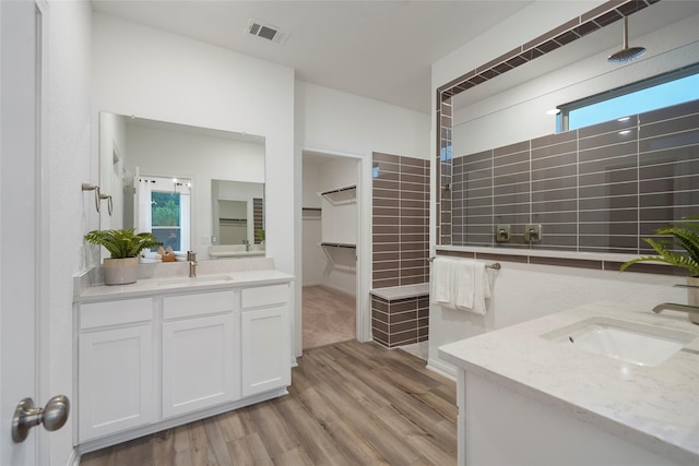 full bath with wood finished floors, a sink, visible vents, and walk in shower