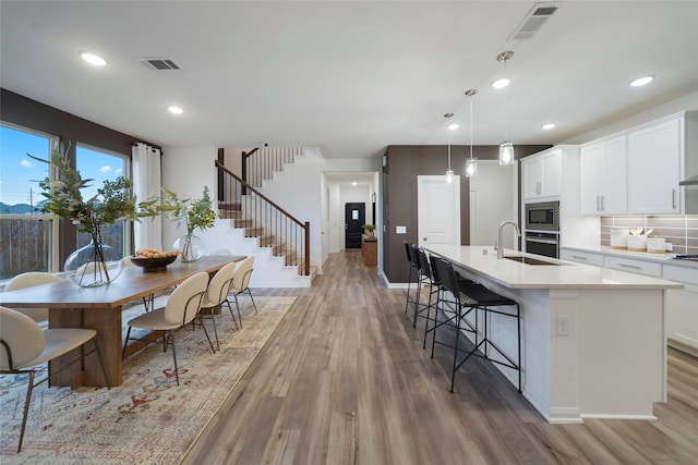 kitchen with visible vents, light wood-style flooring, appliances with stainless steel finishes, and a kitchen island with sink