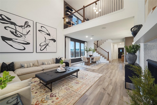 living area with a high ceiling, wood finished floors, and stairway