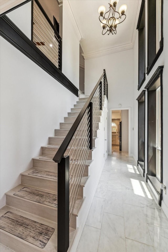 foyer featuring crown molding, a high ceiling, stairway, and a notable chandelier