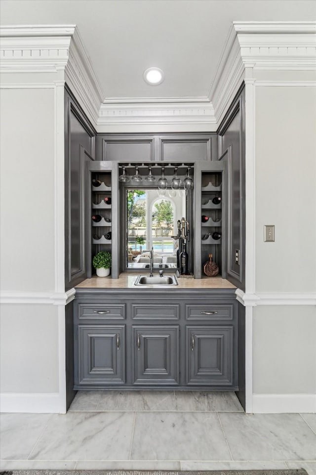 bar with a sink, ornamental molding, baseboards, and bar