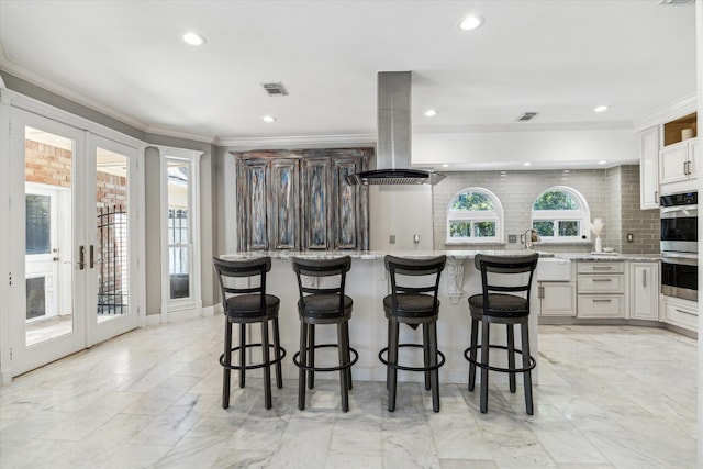 kitchen with french doors, visible vents, island exhaust hood, and backsplash