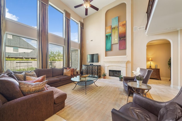 3203 Round Meadow Ln, Missouri City, TX 77459 - living room with a fireplace, a high ceiling, visible vents, ceiling fan, and arched walkways