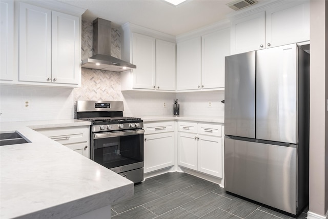 kitchen featuring stainless steel appliances, wall chimney range hood, light countertops, and white cabinets