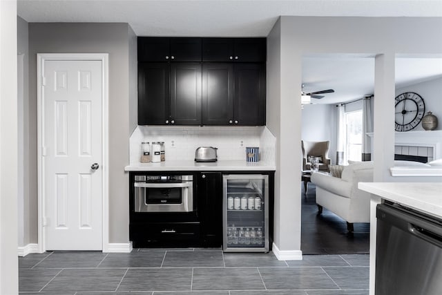 kitchen featuring wine cooler, stainless steel appliances, dark cabinetry, and light countertops