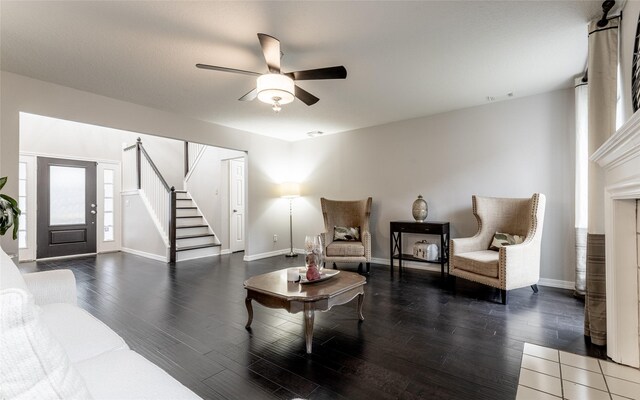 living area featuring stairs, wood finished floors, baseboards, and a ceiling fan