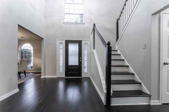 foyer with stairs, a high ceiling, wood finished floors, and baseboards