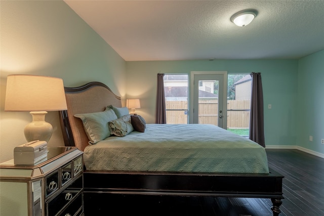 bedroom with access to outside, dark wood-style floors, baseboards, and a textured ceiling