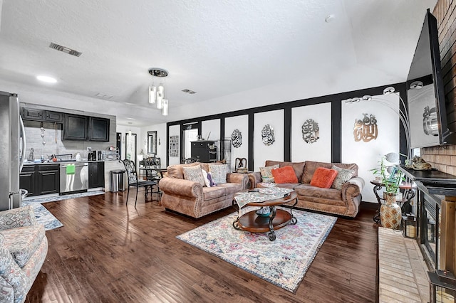 living area featuring visible vents, a textured ceiling, and wood finished floors