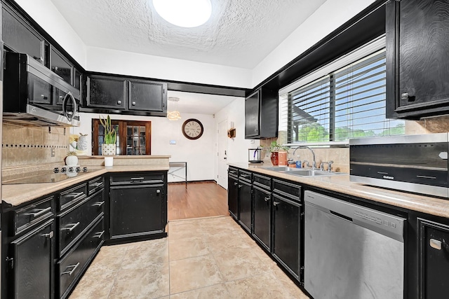 kitchen featuring a sink, light countertops, stainless steel appliances, dark cabinetry, and decorative backsplash