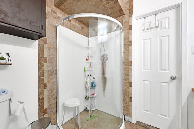 bathroom featuring a shower stall, tile patterned floors, tile walls, and toilet