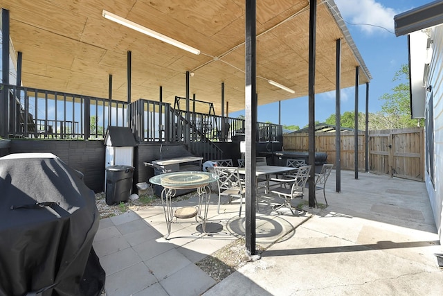 view of patio featuring outdoor dining space, a grill, and fence