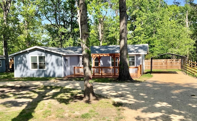 view of front of property featuring a carport, fence, a deck, and driveway