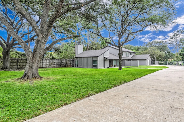 view of yard featuring a garage, fence, and concrete driveway