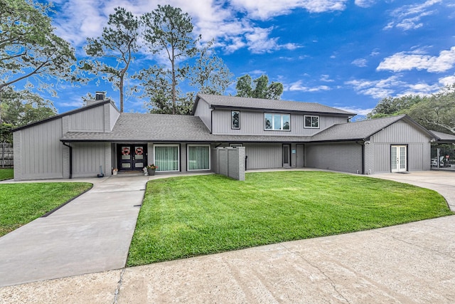 traditional-style house with a shingled roof, a front yard, a chimney, french doors, and driveway