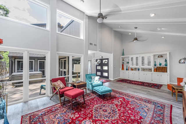 living area featuring beamed ceiling, high vaulted ceiling, a wealth of natural light, and wood finished floors