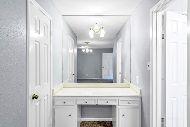 bathroom with an inviting chandelier, a textured wall, and vanity