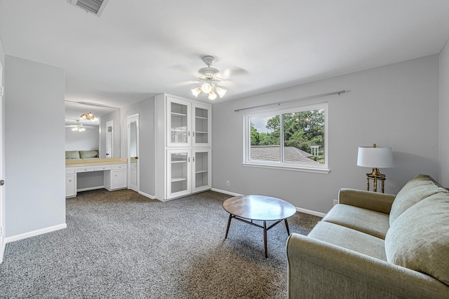 living area featuring ceiling fan, built in desk, dark carpet, baseboards, and visible vents
