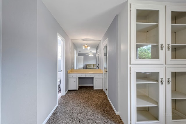 hall featuring dark colored carpet and baseboards