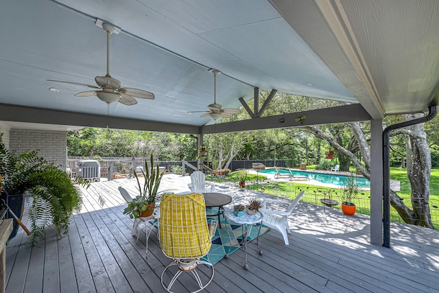 wooden terrace featuring fence, ceiling fan, a fenced in pool, and outdoor dining area