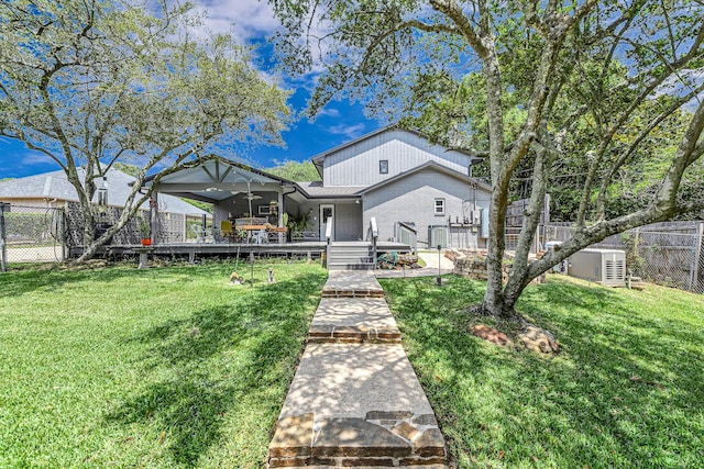 view of front facade featuring brick siding, fence, a wooden deck, and a front yard