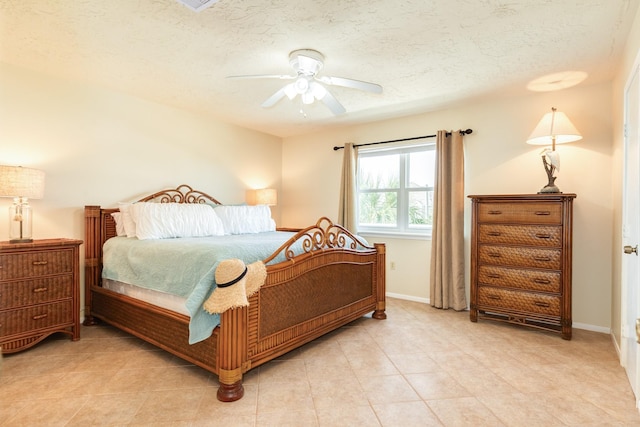 bedroom featuring light tile patterned floors, baseboards, a ceiling fan, and a textured ceiling