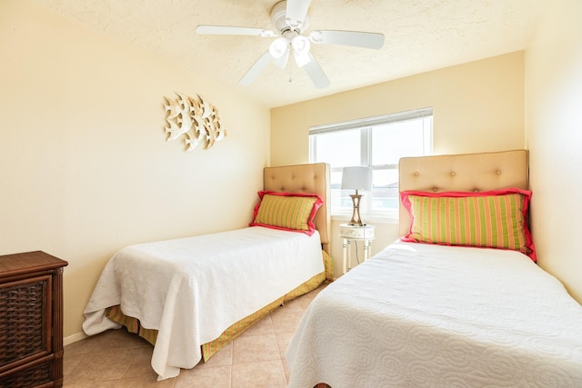 bedroom with baseboards, light tile patterned floors, a textured ceiling, and a ceiling fan