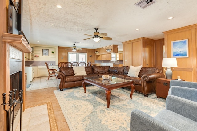 living room with light tile patterned floors, visible vents, a ceiling fan, recessed lighting, and a tile fireplace