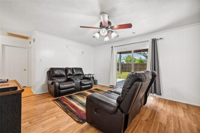 living area with ornamental molding, light wood-style flooring, and ceiling fan