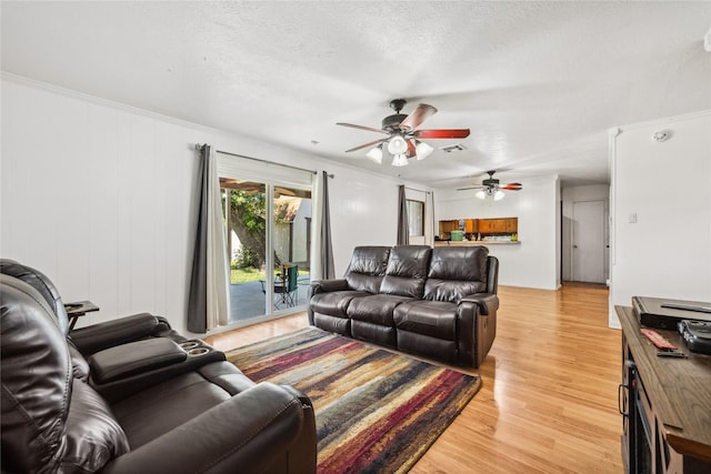 living room featuring visible vents, light wood-type flooring, a textured ceiling, and ceiling fan